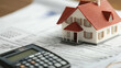 © Jirapron - close up of property valuation document with model house and calculator, symbolizing loan repayment and financial planning