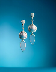 Simple earrings placed floating or flying isolated on light blue background