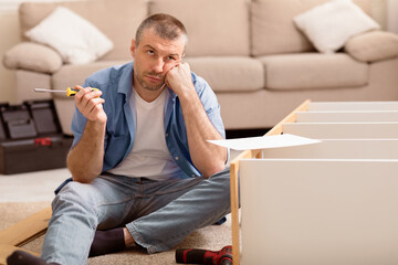 Aufkleber - Unhappy Man Assembling Furniture Himself Having Trouble Installing Cabinet Sitting On Floor At Home. Copy Space