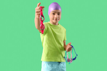 Cute little happy boy with swimming cap and goggles on green background