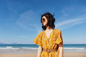 Poster - Woman in Yellow Dress Standing on Beach with Ocean in Background on a Sunny Day