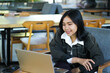 © M Alfan Setyawan - portrait of excited asian woman doing video call online meeting using laptop while sitting in cafe