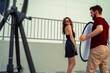 © phoenix021 - Behind the scenes of fashion photoshoot outdoors, attractive female model and male photographer , man holding reflector
