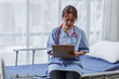 © David - Female doctor or nurse busy about analyzing healthcare treatment on medical documents on bed in hospital