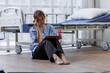 © David - Medical nurse is on bed in hospital sitting down a the hospital corridor in frustration and grief after failure and patient body condition