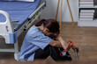 © David - Medical nurse is on bed in hospital sitting down a the hospital corridor in frustration and grief after failure and patient body condition