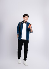 Wall Mural - Full body image of young Asian male student using phone and posing on white background