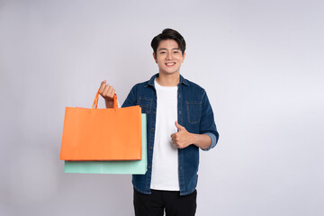 Portrait of young Asian man holding a  shopping bag  and posing on a white background