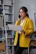 © David - Asian busty employee, Young asian business woman holding paper while working and talking phone at office table, Happy office girl working, business people casual lifestyle