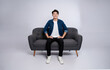 © STOCK88PHOTOGRAPHER - Full body image of young Asian man posing on sofa on white background