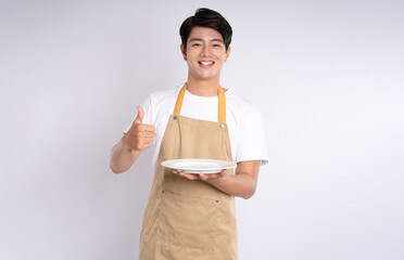 Portrait of young asian man wearing apron and posing on white background