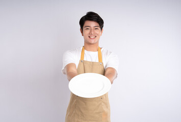 Portrait of young asian man wearing apron and posing on white background