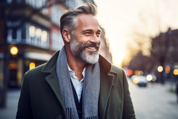 Portrait of a handsome mature man with gray hair and beard wearing a coat in the city