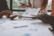 © Phimwilai - Teamwork process Team of business men and women use calculators to calculate numbers, business statistics, profits, cost analysis, graph documents, growth rates. Data chart on the desk.