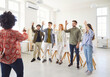© Studio Romantic - Young cheerful colleagues and company employees raising hands to vote at the conference standing in meeting room. Happy smiling business people men and women voting in office during a meeting