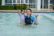 © geargodz - happy mother holding toddler baby girl in her arms while playing water splashing in swimming pool