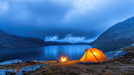 Wall Mural - tent by serene lake at dusk, with a glowing campfire and mountainous backdrop.