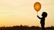 © PBMasterDesign - Child silhouette holding an orange balloon against a sunset background