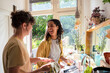 © Westend61 - Happy multiracial friends doing chores in kitchen at home
