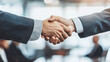 © Ruslan - Two successful businessmen shake hands against colleagues background at negotiating table in office