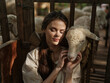 © SHOTPRIME STUDIO - A young woman is holding a sheep in front of a fence with other sheep in the background
