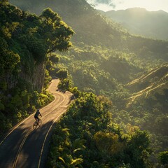 A cyclist rides a winding mountain road through a lush green valley.