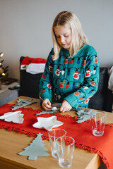 Wall Mural - Young girl setting the table for Christmas dinner, holiday traditions, festive preparation, family rituals, Christmas Eve, childhood memories.