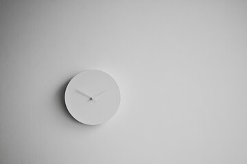 Poster - A minimalist clock with no visible hour markers is mounted on a stark white wall, embodying a sleek and modern aesthetic with an emphasis on simplicity and design.