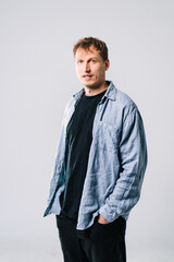 Wall Mural - Confident young man in casual indoor outfit. A young man stands with his hands in pockets, wearing a casual outfit in a bright, indoor space.