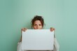 © Edgars - Portrait of a young beautiful brunette woman holding a blank sheet of paper in front of her and looking in to camera. Dressed in white outfit. Front view. Isolated.
