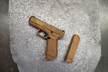 Tactical pistol in coyote color on a metal target at a shooting range.