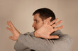 © Yuliia - Frustrated man with disgust on serious face incredulously pushes away troubles with gesture of hands isolated on gray background. Male refuse something bad showing denial.