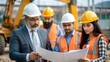 © N7 - An Indian site inspector reviewing plans with a team of workers, with construction equipment in the background.
