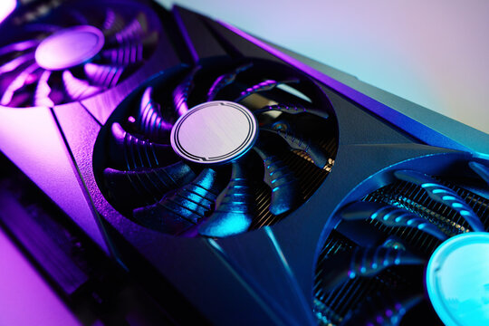 Close-up of high-performance graphics card with three cooling fans with neon lighting. Modern video card for gaming and advanced computing