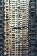 Sticker - An airplane flying over the city skyline with tall buildings and streets below