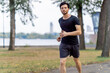 © Guys Who Shoot - on the street in the park in the city center a handsome brunette guy in black shorts and black sweater on a morning jog