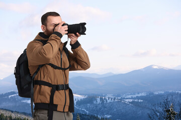 Man with backpack taking photo in mountains