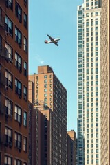 Poster - A plane flying over a city with tall buildings
