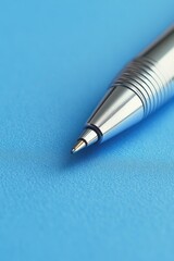 Fototapete - A silver pen sits atop a blue surface, ready for use