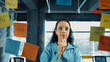 © Summit Art Creations - Portrait of skilled young beautiful hispanic project manager thinking about marketing idea. Professional businesswoman making business plan by using sticky notes at glass board in office. Manipulator.