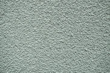 A grey wall with a rough texture. The wall is covered in small bumps and ridges, giving it a somewhat uneven appearance. The texture of the wall is not smooth, but rather rough and bumpy.