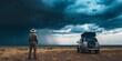© irissca - Storm chaser observes an approaching storm near a vehicle in a vast landscape