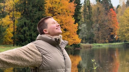 Wall Mural - Happy young woman enjoying autumn weather and walking in the park