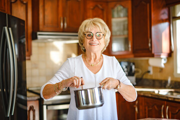 Happy senior woman preparing lunch in modern kitchen cooking for the family at home