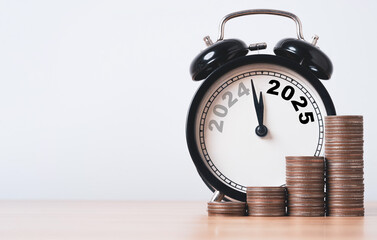 Wall Mural - 2024 and 2025 on black alarm clock on wooden table with coins stacking for financial preparation of 