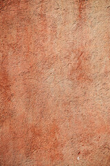 Wall Mural - A close-up of a textured, red-orange wall showcasing rich, earthy tones and a rough, uneven surface. 