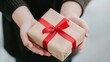 © PJ Gallery - Gift Wrapped with Red Ribbon Held in Hands