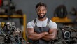 © javu - Smiling mechanic in workshop, arms crossed, surrounded by machinery.