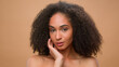 © Yuliia - Female beauty portrait African American ethnic woman model beautiful attractive girl with perfect smooth skin make-up haircare skincare curly hair curls posing in studio beige background face cosmetic
