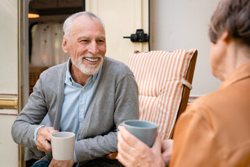 Smiling old elderly senior couple spouses talking drinking tea while driving camper van trailer